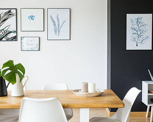 interior of a dining area with a wooden table and images of plants on the walls