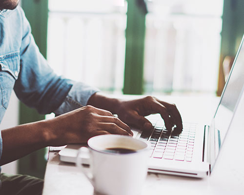 man wearing blue typing at his computer