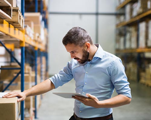 man wearing a blue shirt checking inventory in a warehouse