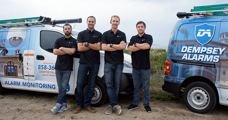 four employees of Dempsey alarms standing in front of two vans